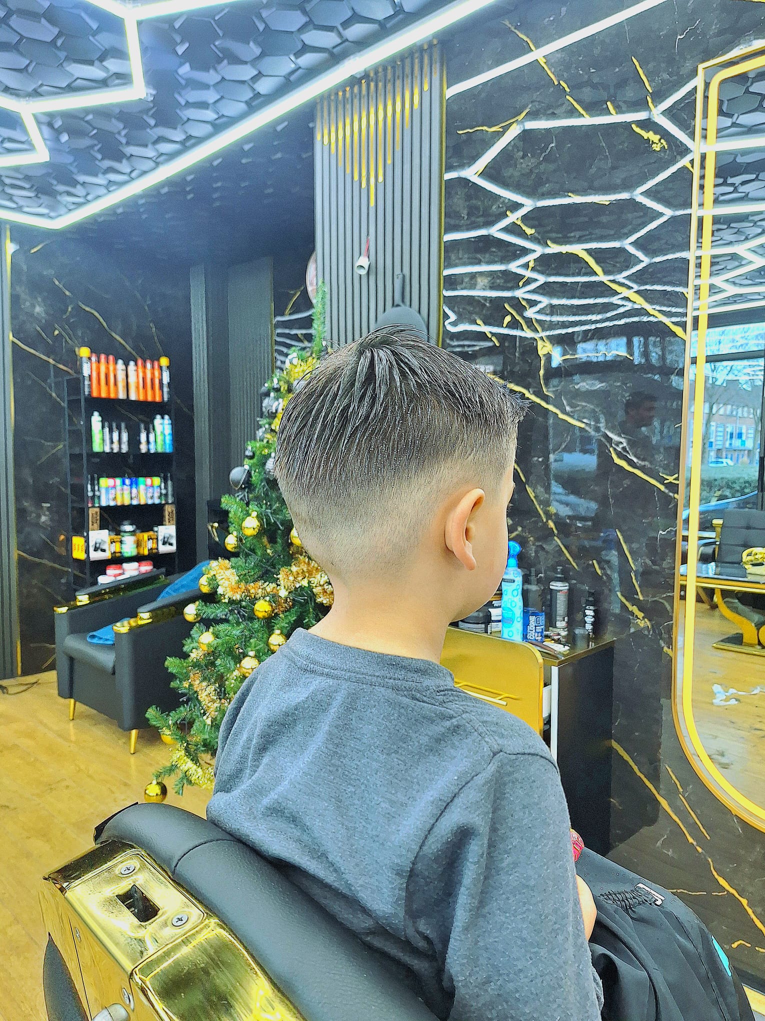 Een jongen in de kappersstoel, van achteren gezien, met een strak bijgewerkte fade.